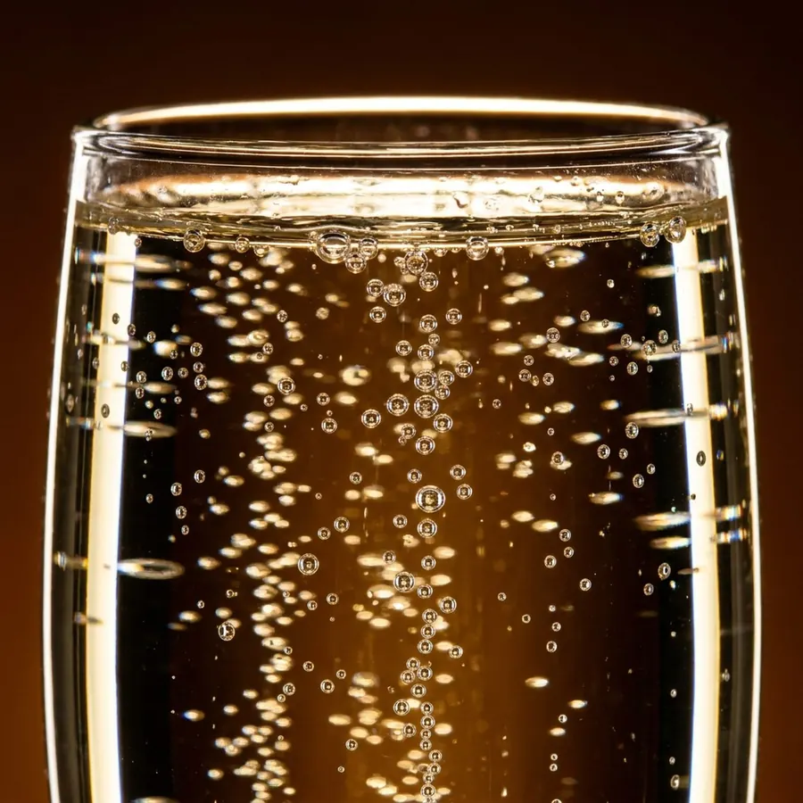 A glass of water mid-effervescence, backlit against dark brown